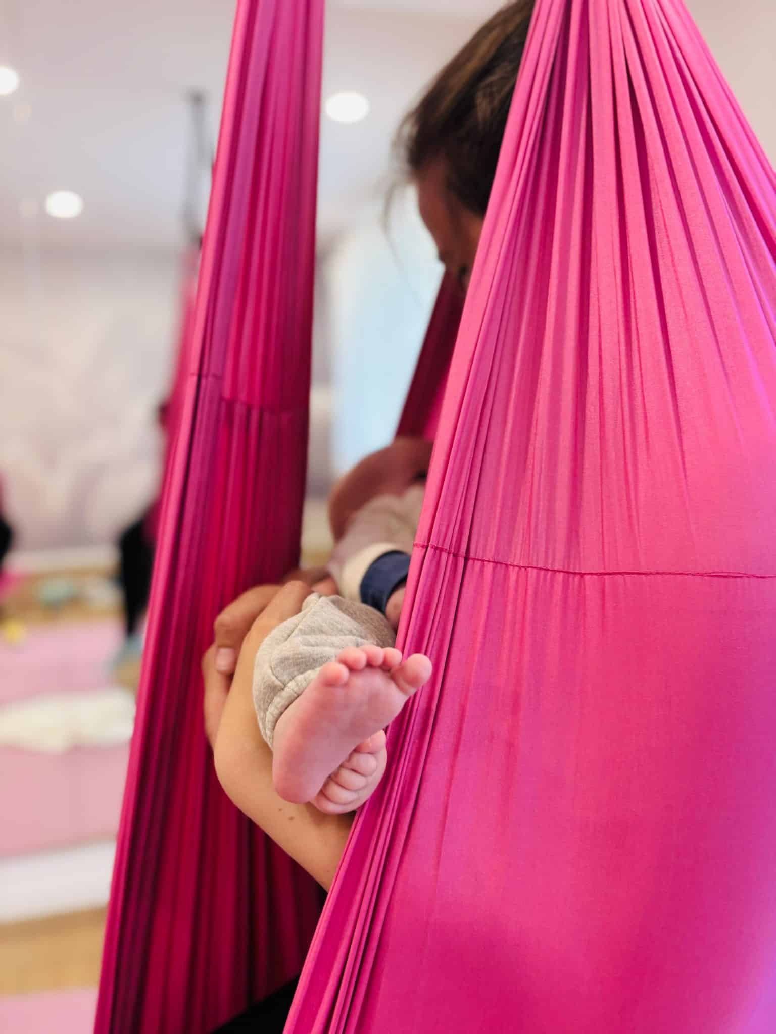 Eine Mama mit Baby im Arm in einem Aerial-Tuch bei der Rückbildung